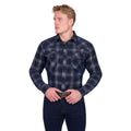 A man wearing the Pure Western Mens Harley L/S Shirt (P6W1100166) in Navy/Tan and dark jeans stands against a white background, looking to the side with his hands on his belt buckle.