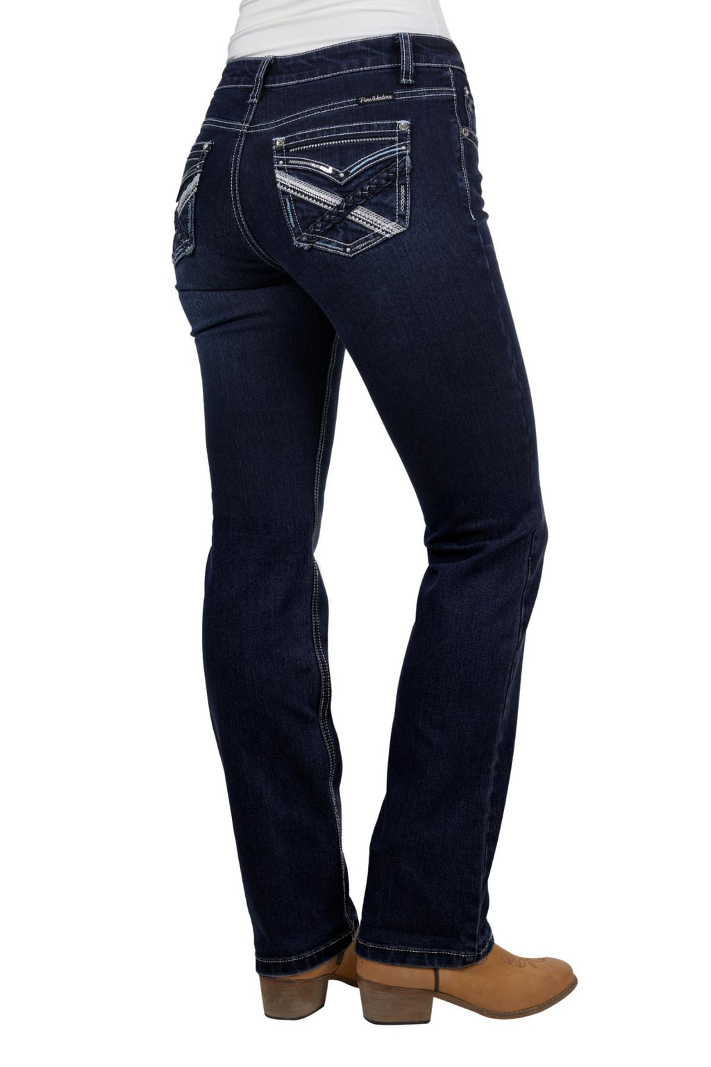 A woman wearing Pure Western Womens Kim Hi Rise Bootcut Jeans - 34 Leg (PCP2213852) Midnight, featuring decorative back pocket stitching, and tan heeled boots, photographed from the back.