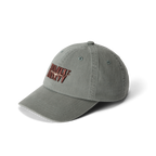 The R.M.Williams Heritage Twill Cap (ACX9OWI27) in slate is made from organic cotton twill and features embroidered red and white "DAILY REVV" text on the front, shown against a white background.