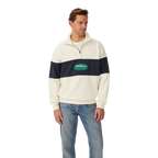 A man stands against a white background wearing the R.M.Williams Men's 90s Logo 1/4 Zip Jumper in ecru with a navy chest and sleeve stripe, paired with light blue jeans.