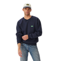 A man stands against a plain white background wearing a vintage navy R.M.Williams Mens 90s Logo Crew Jumper (KCU00BB01), light blue jeans, and a light gray cap.