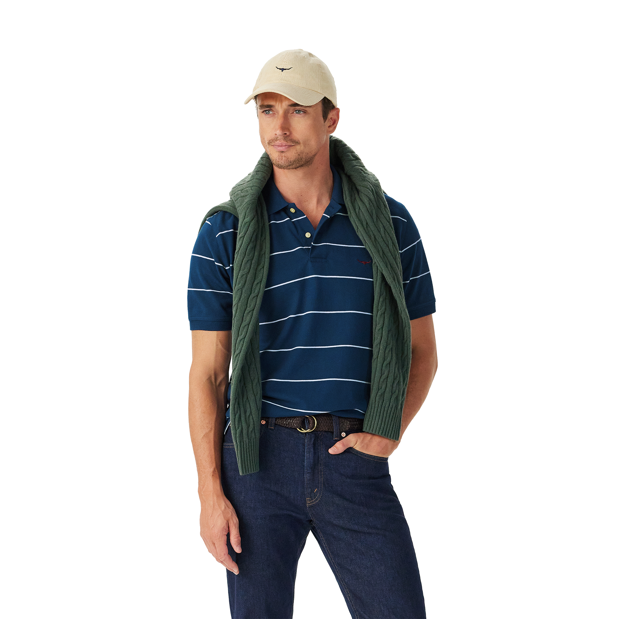 A man in a beige cap, dark jeans, and green sweater draped over his shoulders stands against a white background wearing the R.M.Williams Mens Albany Stripe Polo (KP210QS10) in Vintage Blue for a classic, relaxed look.