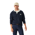 Man wearing a navy R.M.Williams Classic Shoulder Rugby with an R.M.Williams logo, beige cap, brown leather belt, and dark jeans on a white background. R.M.Williams Mens Classic Shoulder Rugby (KR200RJ4502) Navy