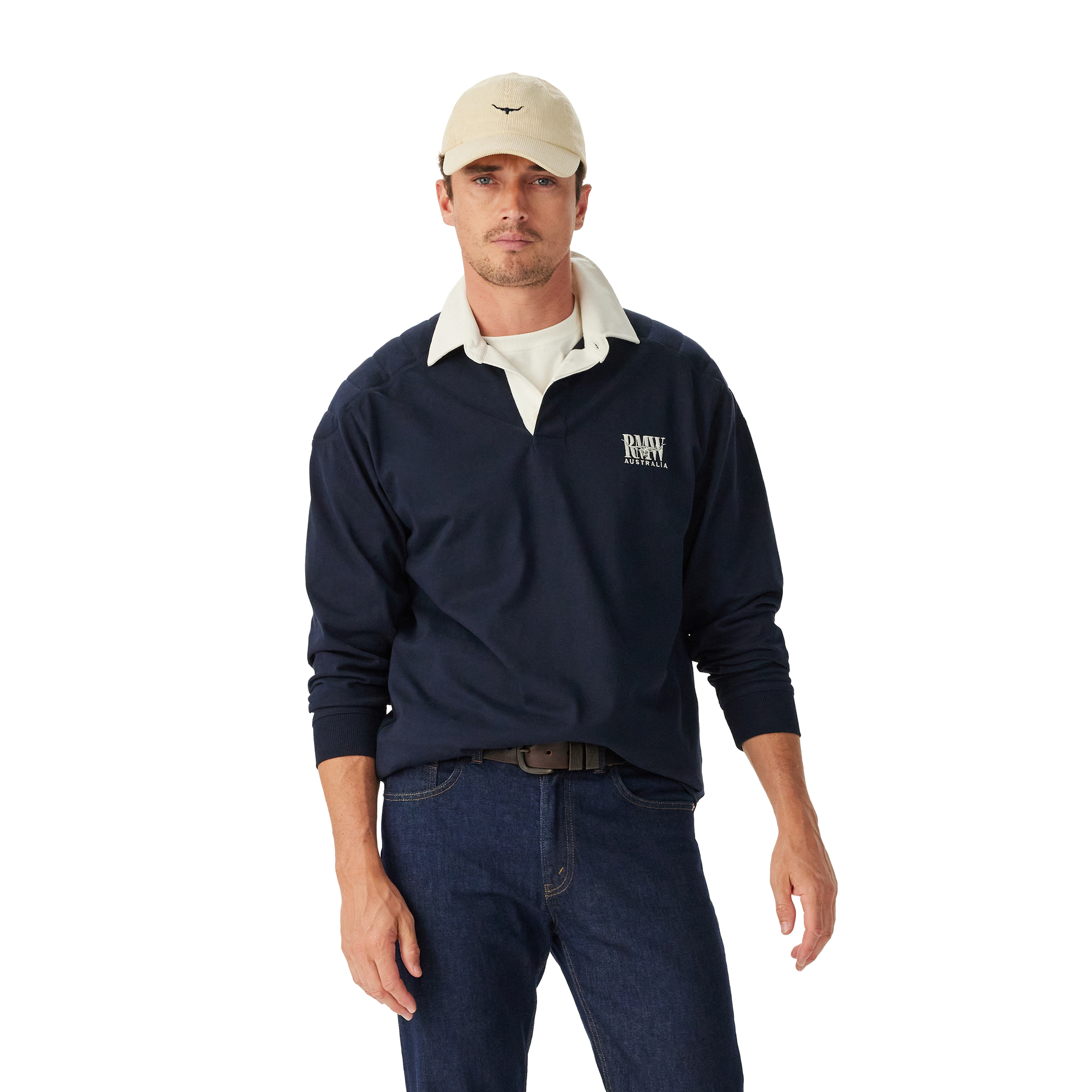 Man wearing a navy R.M.Williams Classic Shoulder Rugby with an R.M.Williams logo, beige cap, brown leather belt, and dark jeans on a white background. R.M.Williams Mens Classic Shoulder Rugby (KR200RJ4502) Navy