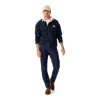 Man wearing a navy R.M.Williams Classic Shoulder Rugby with an R.M.Williams logo, beige cap, brown leather belt, brown boots and dark jeans on a white background.  R.M.Williams Mens Classic Shoulder Rugby (KR200RJ4502) Navy