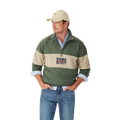 A man in a beige cap, blue jeans, and a light blue shirt layered under the R.M.Williams Mens Heritage 1/4 Zip Sweatshirt (KZU00BB02) in Spruce Green stands with his hands in his pockets against a plain white background.