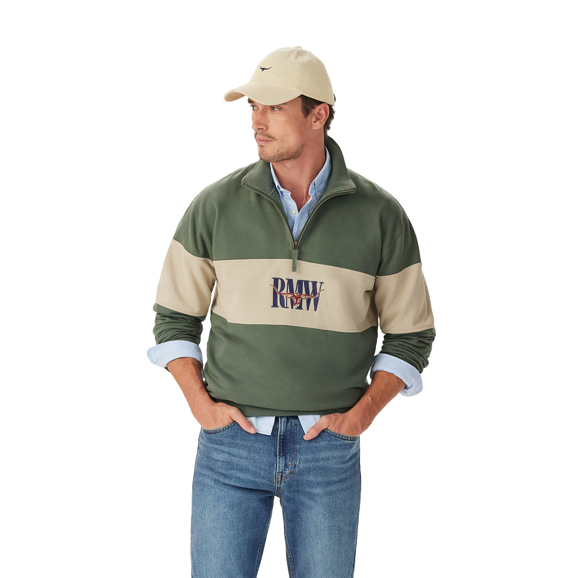 A man in a beige cap, blue jeans, and a light blue shirt layered under the R.M.Williams Mens Heritage 1/4 Zip Sweatshirt (KZU00BB02) in Spruce Green stands with his hands in his pockets against a plain white background.
