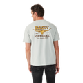 A man in black jeans faces away, wearing the R.M.Williams Mens Louth S/S Tee (KDU10JE05) Salt—a light grey, relaxed fit tee with a yellow graphic and "RMW EST. 1932 GENUINE Boots, Saddles, Clothes" above a longhorn skull on the back.