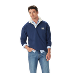 A man stands casually with one hand in his pocket, wearing the R.M.Williams Mens Mulyungarie 1/4 Zip Sweatshirt (KZU00BB03) in Vintage Blue over a light blue shirt and blue jeans, against a plain white background.