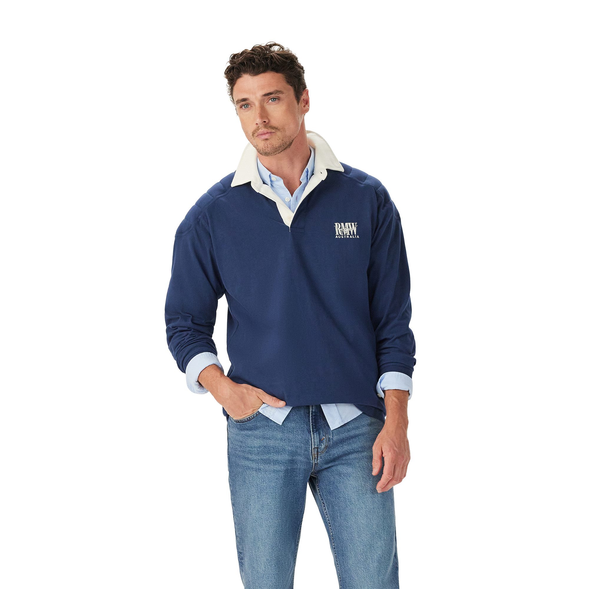 A man stands casually with one hand in his pocket, wearing the R.M.Williams Mens Mulyungarie 1/4 Zip Sweatshirt (KZU00BB03) in Vintage Blue over a light blue shirt and blue jeans, against a plain white background.