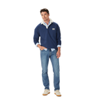 A man stands casually with one hand in his pocket, wearing the R.M.Williams Mens Mulyungarie 1/4 Zip Sweatshirt (KZU00BB03) in Vintage Blue over a light blue shirt and blue jeans, against a plain white background.