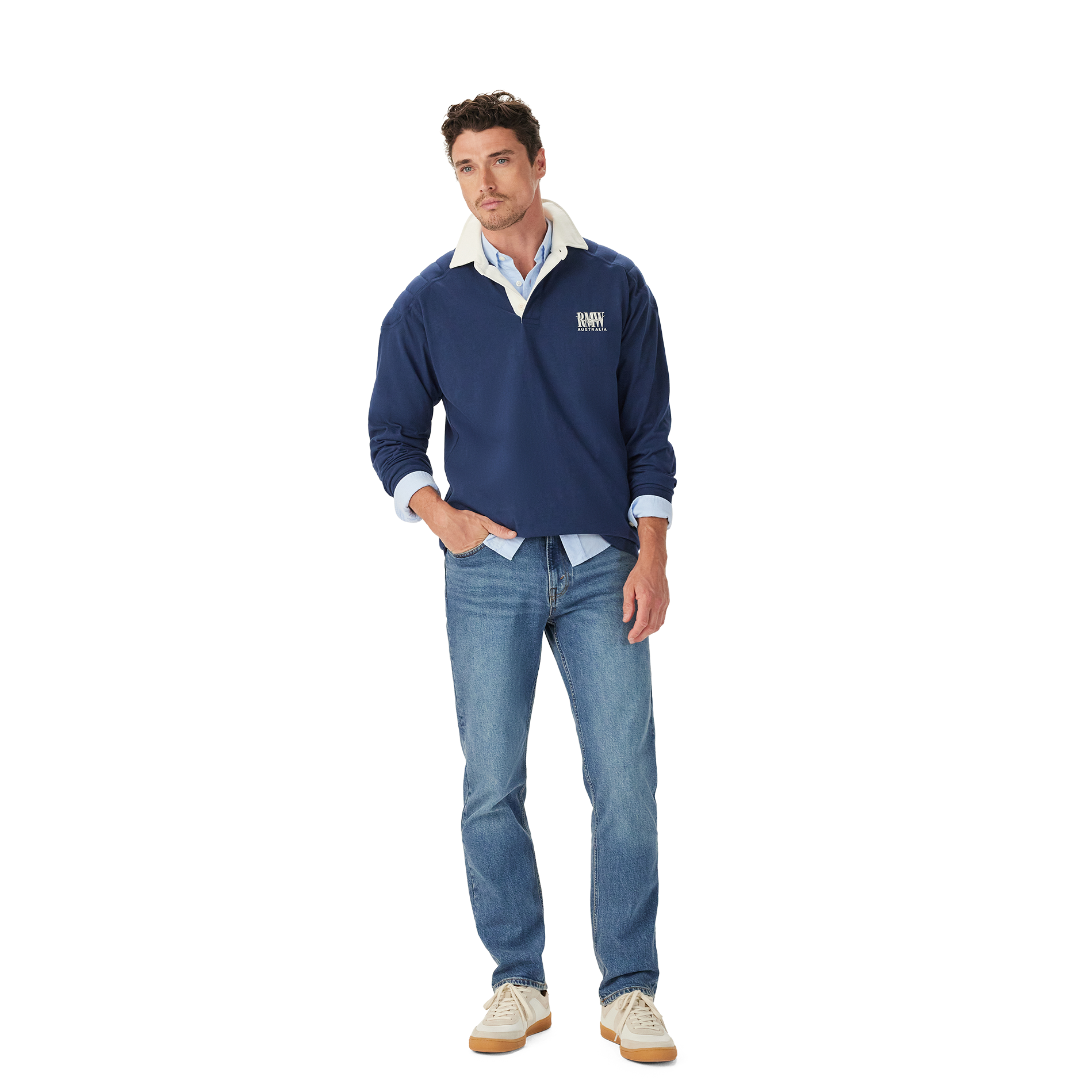 A man stands casually with one hand in his pocket, wearing the R.M.Williams Mens Mulyungarie 1/4 Zip Sweatshirt (KZU00BB03) in Vintage Blue over a light blue shirt and blue jeans, against a plain white background.