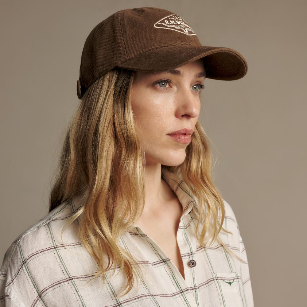 A woman modelling an R.M.Williams Original RMW Heavy Twill Cap (ACX9OCT05) in Cinnamon.