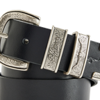 A coiled black R.M.Williams Western Drover Belt (BSF5DCH02) with engraved and embossed silver toned buckle and keepers on a white background.