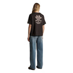 A woman from behind wearing a dark chocolate R.M.Williams Kandos Short Sleeve Tee (KDX10JE06) with a large back logo print of the RMW longhorn, paired with denim jeans, photographed on a white background.
