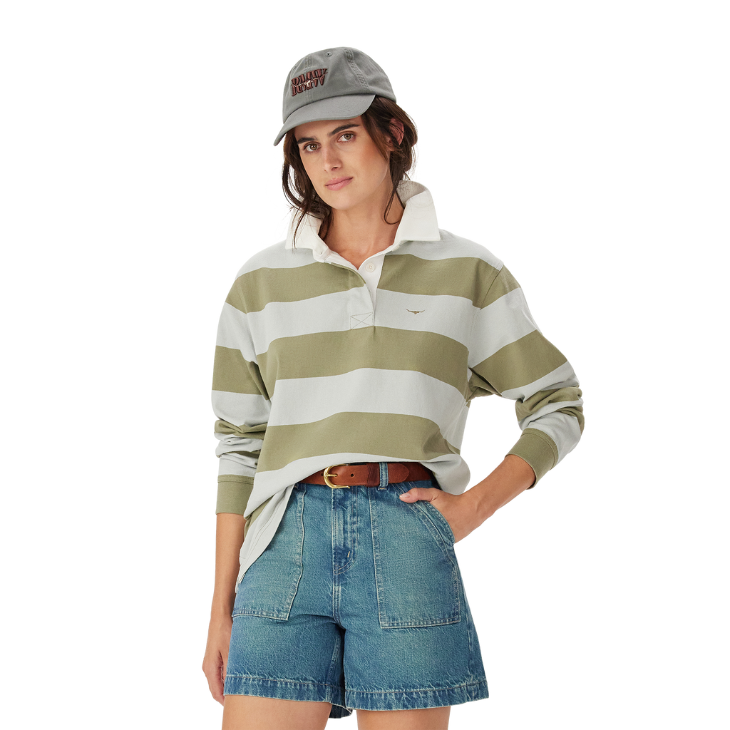 A woman wearing the R.M.Williams Womens Narran Stripe Rugby (KRR00RJ01) in Lichen stands with one hand on her hip against a plain white background.
