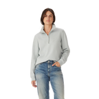 A woman with straight brown hair and a neutral expression wears the R.M.Williams Womens Trickett 1/4 Zip Sweatshirt (Salt) and blue jeans, standing against a plain white background with one hand in her pocket.