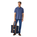 A man holding a Navy R.M.Williams Heritage Tote (CGM9OCA04) with brown handles and RMW logo on a white background.