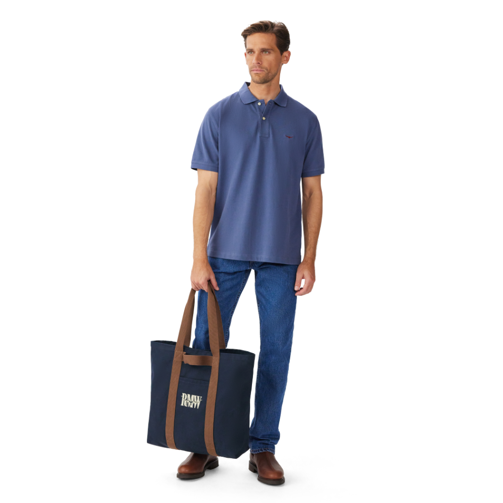 A man holding a Navy R.M.Williams Heritage Tote (CGM9OCA04) with brown handles and RMW logo on a white background.