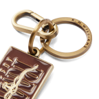 A close up of an R.M.Williams Men's Heritage Logo Enamel Keyring (CKS4AMT01) with a brass clasp and a brown enamel tag featuring 'R.M. Williams Australia' on a white background.