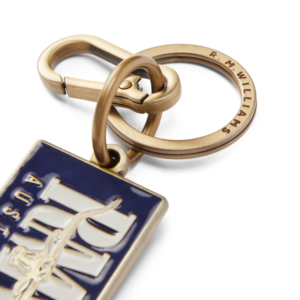 A close up on an R.M.Williams Men's Heritage Logo Enamel Keyring (CKS4AMT02) in blue enamel featuring 'RMW Australia' on a white background