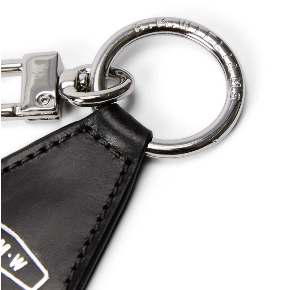 Close up detail of a black leather R.M.Williams Men's Keyfob (CKS4MLE03) with metal ring and clip on a white background.