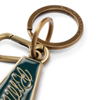 Close up detail of a brass and pine green R.M.Williams Men's Rope Logo Enamel Keyring (CKS4AMT01) with cursive RMWilliams text on a white background.