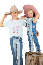 Two young children in cowboy hats and brown boots smile at the camera. One stands on a tree stump, the other on the ground. Both wear Ringers Western Children's Ella Panel Flare Jeans in Vintage Light Blue/Dark Mid Blue, showing classic western style.