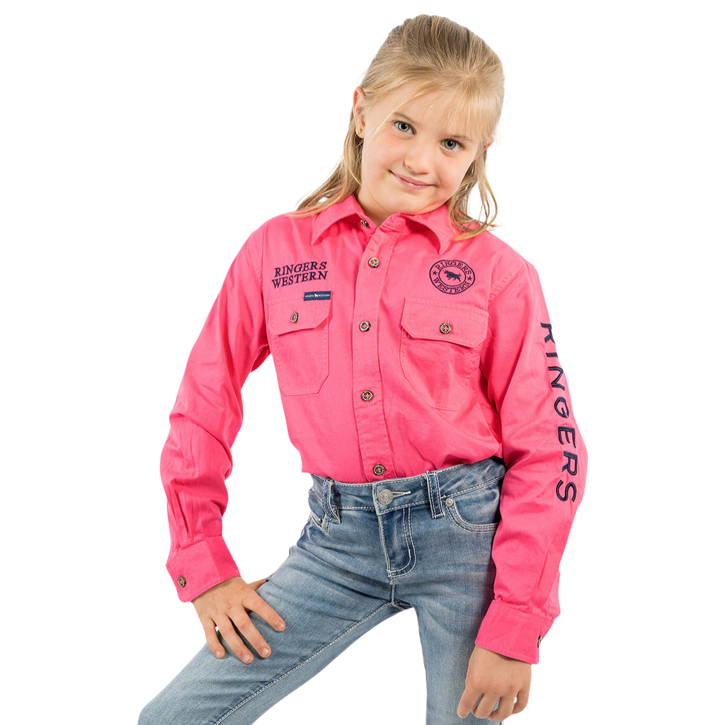 Smiling young girl in a Ringers Western Childrens Jackaroo Full Button L/S Work Shirt (Melon/Navy Embroidery) and blue jeans, standing with one hand on her hip against a white background.