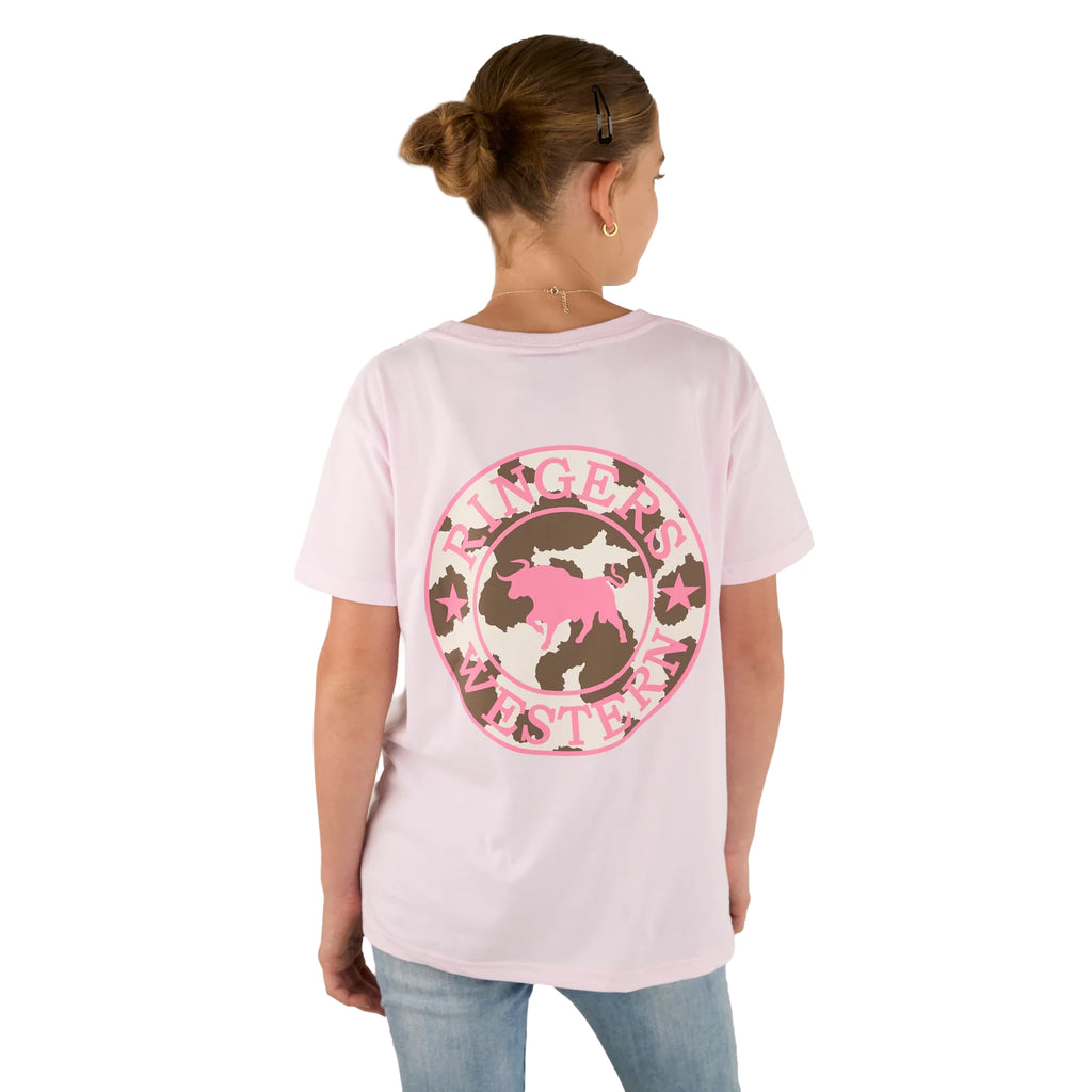 A girl with a bun wears the Ringers Western Childrens Signature Bull Classic Fit S/S Tee in Barely Pink, featuring a bull logo on the back. She faces away from the camera and pairs it with light blue jeans.