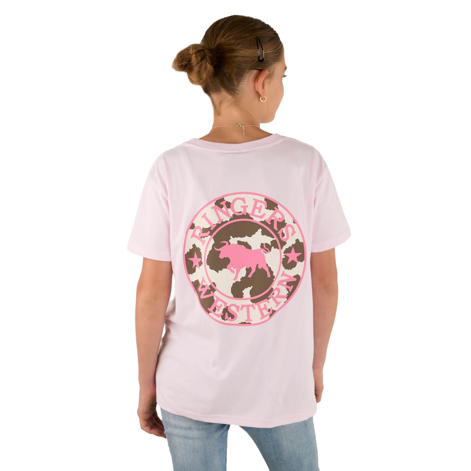 A girl with a bun wears the Ringers Western Childrens Signature Bull Classic Fit S/S Tee in Barely Pink, featuring a bull logo on the back. She faces away from the camera and pairs it with light blue jeans.