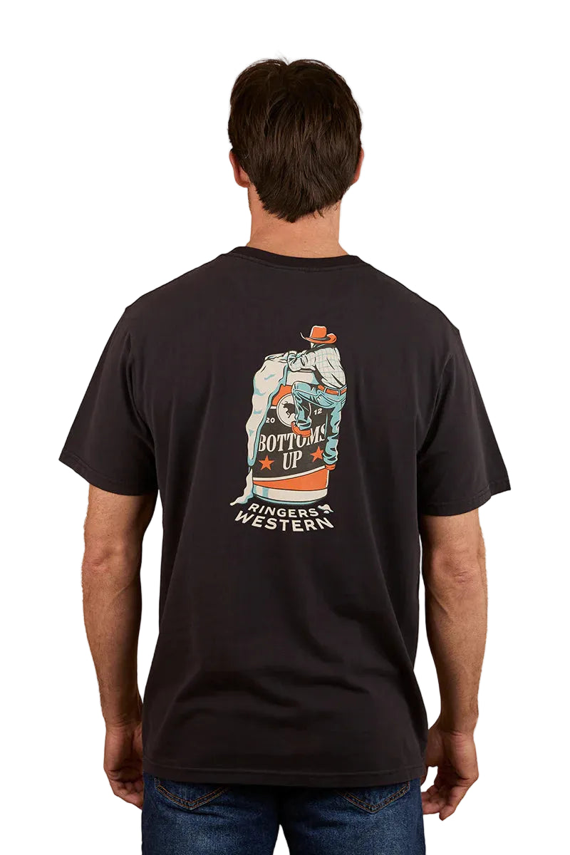 A man is seen from the back wearing a Ringers Western Mens Bottoms Up Loose Fit S/S Tee in washed black, featuring a colorful hand holding a can graphic with "Bottoms Up" and "Ringers Western" printed beneath.