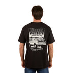A man wears the Ringers Western Mens Get Your Truck On Loose Fit Tee in black, featuring a pickup truck graphic and "Ringers Western, Truckin' Since 2012, Get your truck on" on the back, embodying a relaxed country vibe.