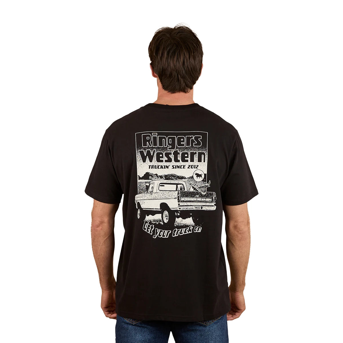 A man wears the Ringers Western Mens Get Your Truck On Loose Fit Tee in black, featuring a pickup truck graphic and "Ringers Western, Truckin' Since 2012, Get your truck on" on the back, embodying a relaxed country vibe.