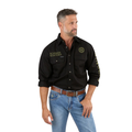 A man wears the Ringers Western Mens Hawkeye Full Button L/S Work Shirt (118110002) in Black/Camo with light blue jeans and a brown belt. He has short hair, a trimmed beard, rolled-up sleeves, and looks off to the side.