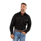 A man with short hair and a beard wears a Ringers Western Mens King River L/S Full Button Workshirt (171110001) in Black, light blue jeans, and a brown belt, standing with one hand in his pocket against a white background.