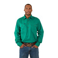 A man wears the Ringers Western Mens King River Half Button Work Shirt in green with blue jeans and a brown belt with a large buckle. He faces forward, smiling with his hands in his pockets, against a plain white background.