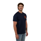 A man wearing a navy blue Ringers Western Men's Signature Bull Loose Fit S/S Tee (120201560) with an orange circular graphic that reads 'Ringers Western' with a bull silhouette, paired with blue jeans against a plain white background.