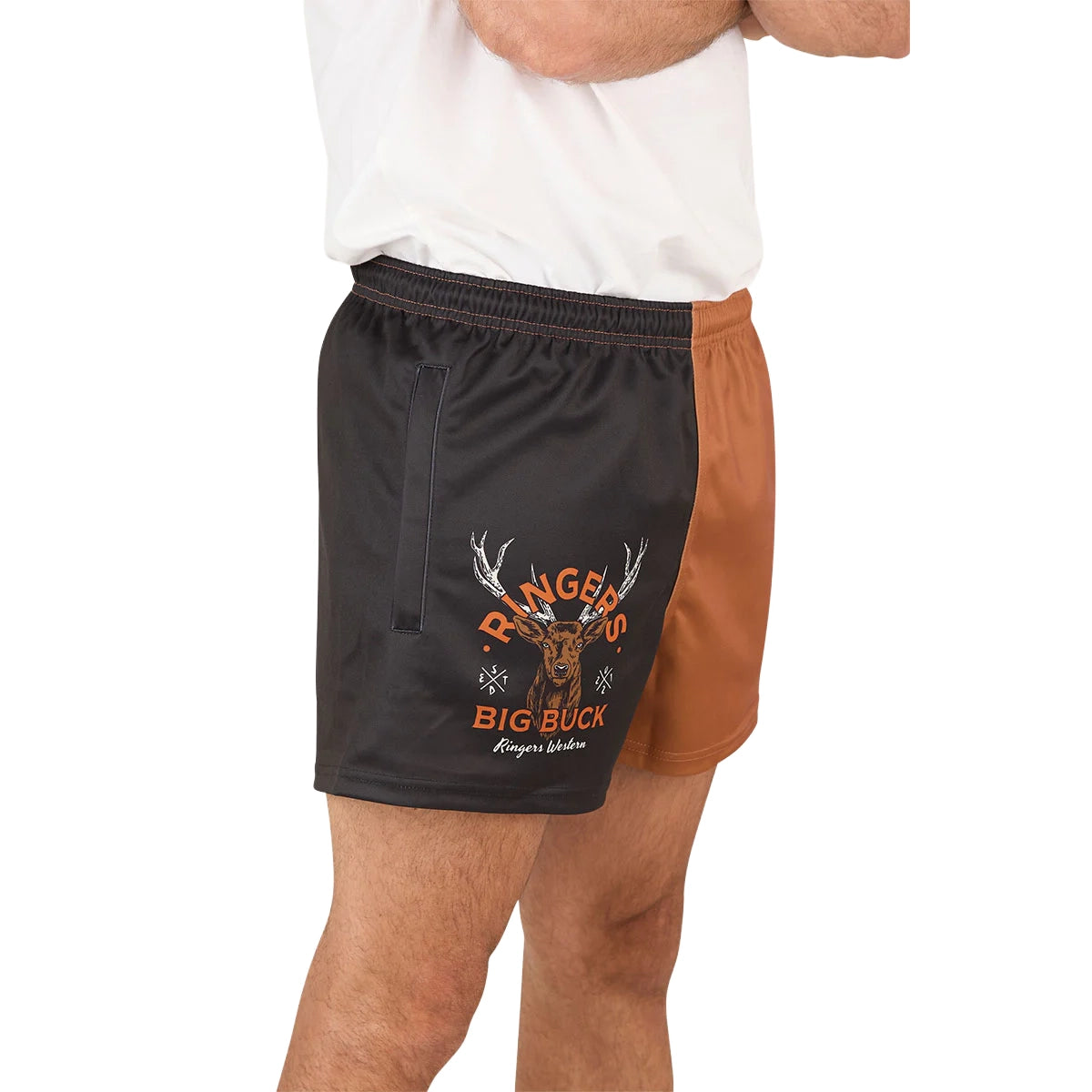 A person wearing a white shirt and Ringers Western Unisex Big Buck Footy Shorts (125019RW) in Tobacco, made from moisture-wicking polyester. Only the lower torso and upper legs are visible, highlighting a sporty country style.