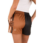 A person wearing a white shirt and Ringers Western Unisex Big Buck Footy Shorts (125019RW) in Tobacco, made from moisture-wicking polyester. Only the lower torso and upper legs are visible, highlighting a sporty country style.