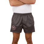 A person wears a white T-shirt and Ringers Western Unisex Big Ringers Footy Shorts (125025RW) in Charcoal/Pink with a pink circular logo on the left leg, arms crossed. The photo is cropped at the chest.