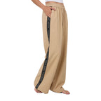A woman in profile wearing beige Ringers Western Alexis Elastic Waist Wide Leg Pants (225045RW) with a black side stripe featuring Ringers Western text, shown from the waist down against a plain white background.