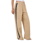 A woman from 3-4 front wearing beige Ringers Western Alexis Elastic Waist Wide Leg Pants (225045RW) with a black side stripe featuring Ringers Western text, shown from the waist down against a plain white background.