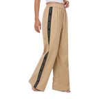 A woman in profile wearing beige Ringers Western Alexis Elastic Waist Wide Leg Pants (225045RW) with a black side stripe featuring Ringers Western text, shown from the waist down against a plain white background.