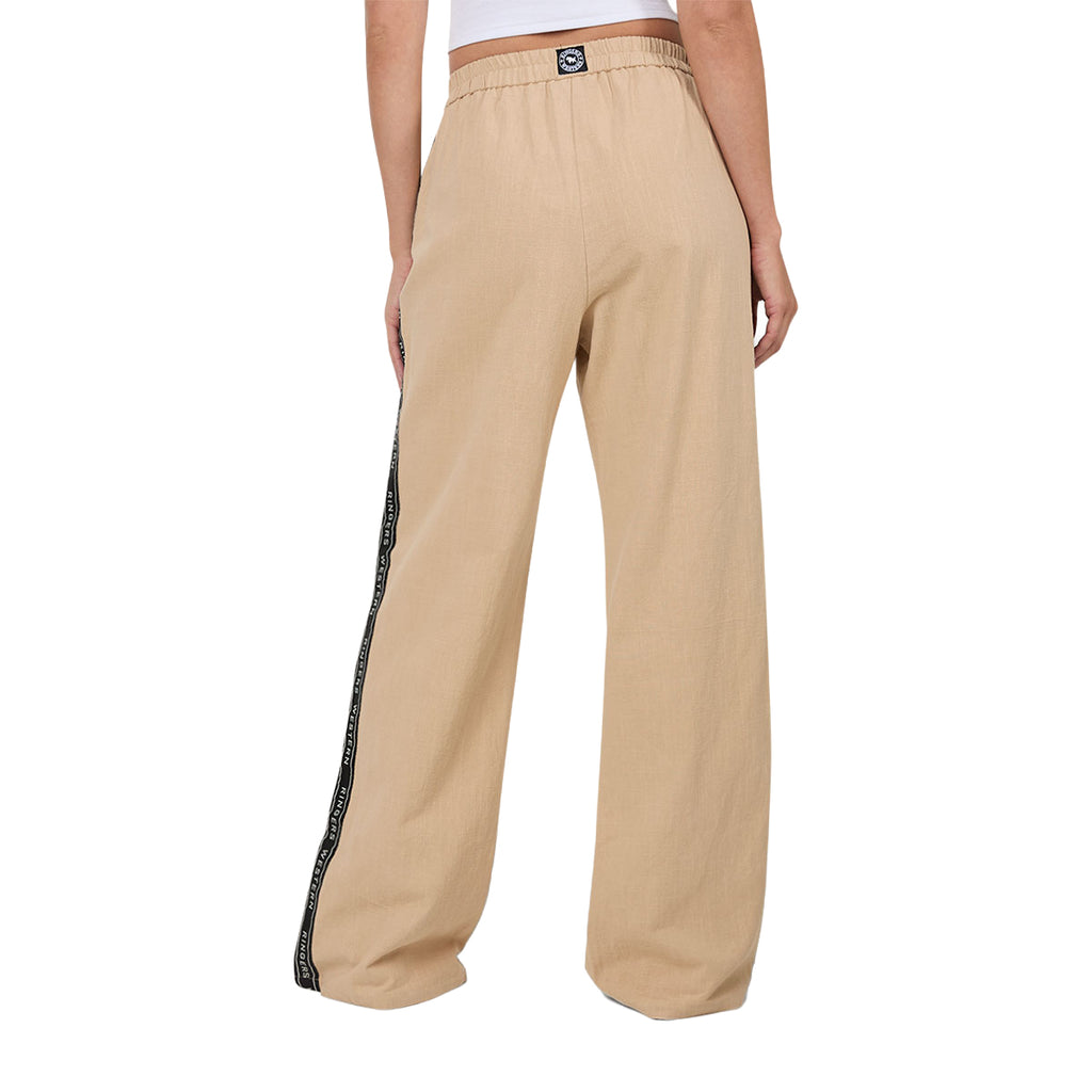 A woman viewed from behind wearing beige Ringers Western Alexis Elastic Waist Wide Leg Pants (225045RW) with a black side stripe featuring Ringers Western text, shown from the waist down against a plain white background.