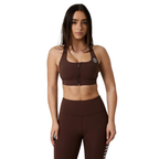 A woman modeling a matching brown activewear set consisting of a front-zip sports bra and high-waisted leggings, shown against a plain white background.