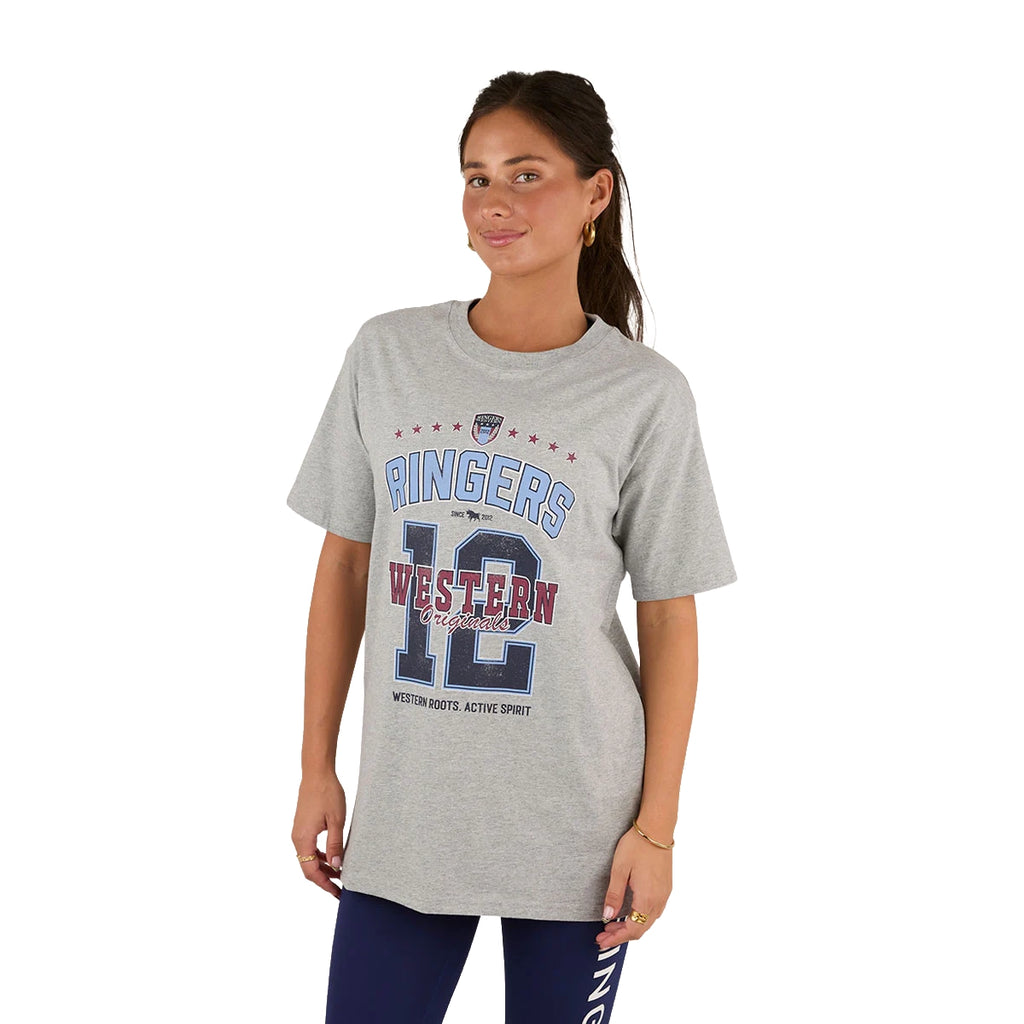 A woman wears the Ringers Western Womens Division Oversized S/S Sport Tee (225018RW) in grey marle, featuring "Ringers Western 12" and red, white, blue graphics. She pairs it with dark leggings and stands facing forward with a slight smile.