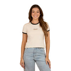 A woman with long brown hair wears the Ringers Western Womens Mae Ringer S/S Tee in Off White/Orange, paired with light blue jeans. She is smiling and standing against a plain white background.