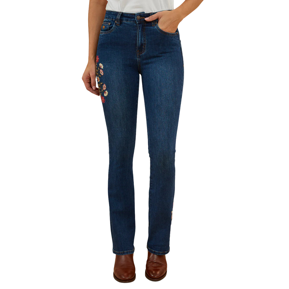 A woman wearing classic blue Ringers Western Women's Penny Rodeo High Rise Bootleg Jeans (222104RW) showing colourful floral embroidery on the right side thigh and left ankle, paired with brown leather boots against a plain white background.