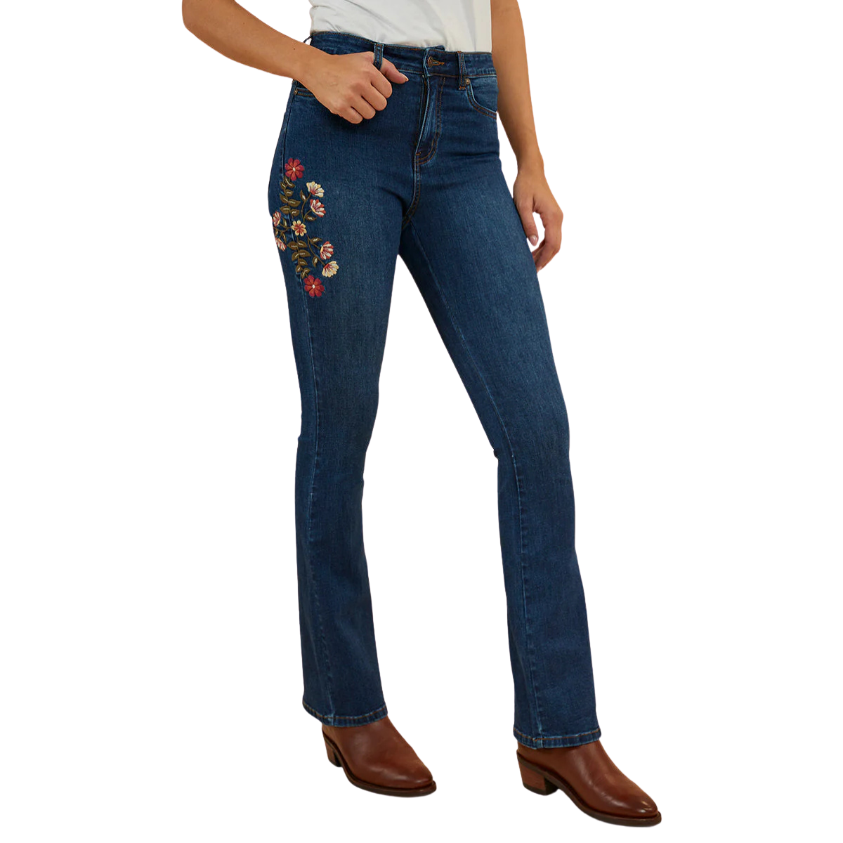 A woman wearing classic blue Ringers Western Women's Penny Rodeo High Rise Bootleg Jeans (222104RW) showing colourful floral embroidery on the right side thigh, paired with brown leather boots against a plain white background.